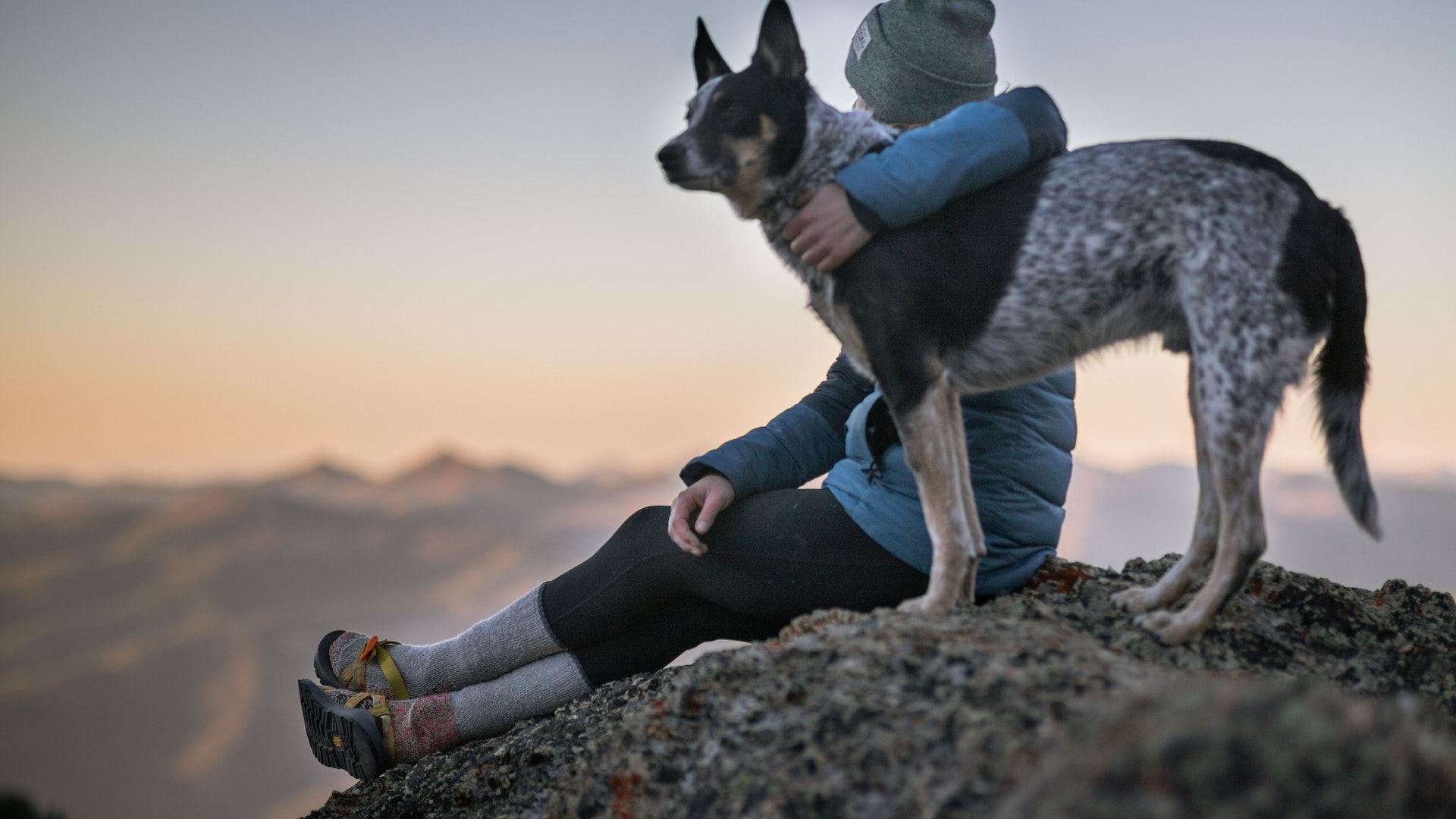Woman in tecking outfit with her dog looking at the stunning view