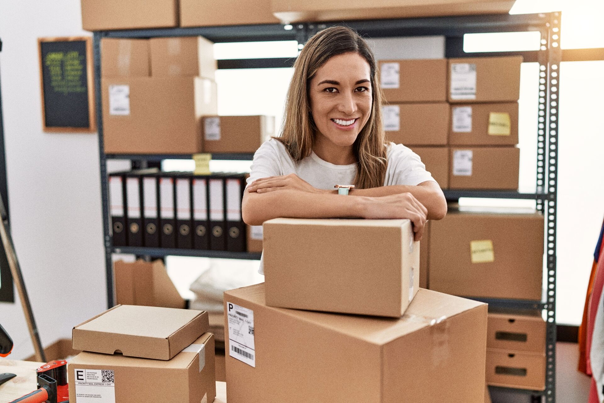 Young woman smiling confident leaning on delivery package at store
